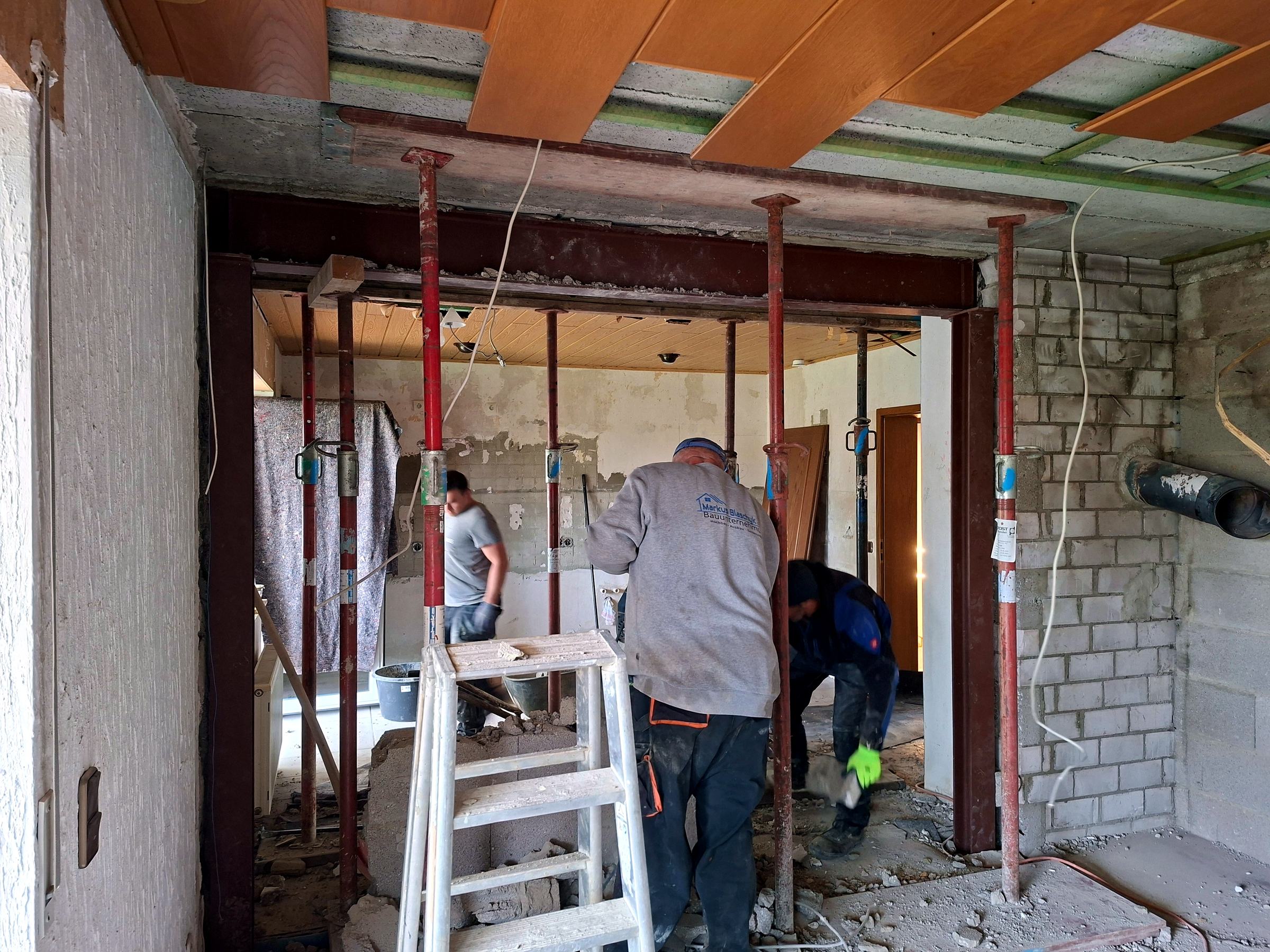 Mitarbeiter im Firmenpullover bei einem Wanddurchbruch im Einfamilienhaus
