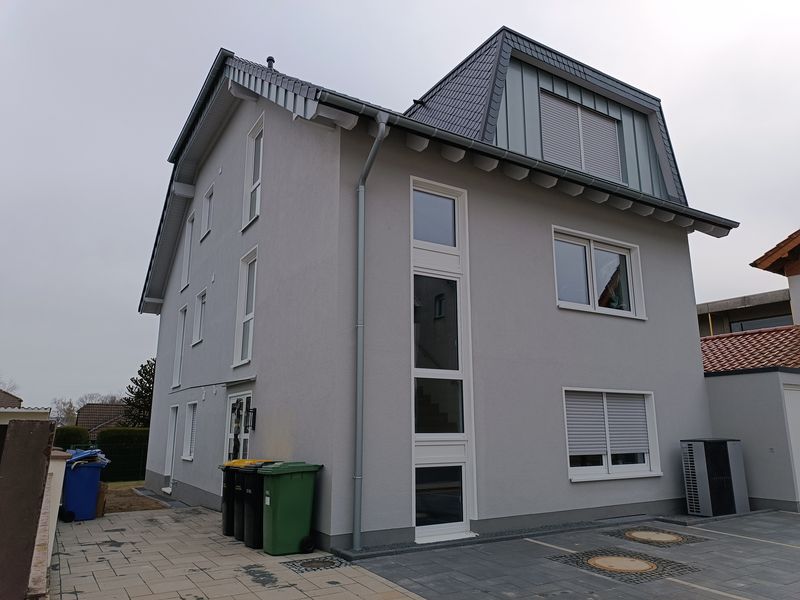 Fertiggestelltes Mehrfamilienhaus mit hellgrauer Fassade